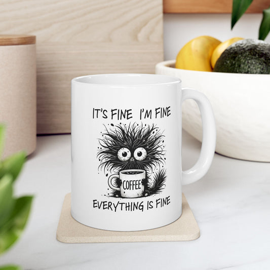 Close-up of funny coffee mug with frazzled character holding cup and text “It’s Fine I’m Fine Everything Is Fine.”