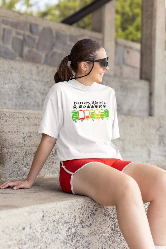 Woman sitting wearing "Battery Life of a Runner" shirt – motivational running tee with weekday battery icons