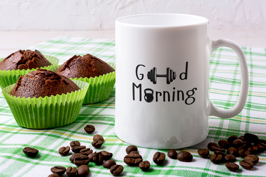 White ceramic mug with the phrase “Good Morning” placed beside muffins and coffee beans – cozy breakfast coffee cup by FitBOUND