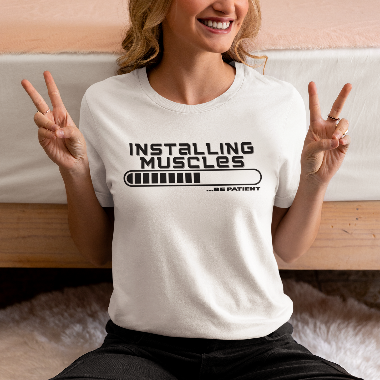 Smiling woman wearing “Installing Muscles” shirt – humorous gym tee for beginners and athletes