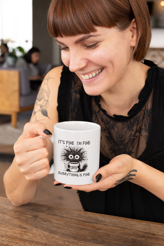 Young woman smiling while holding a funny coffee mug with text “It’s Fine I’m Fine Everything Is Fine” – perfect quirky gift.