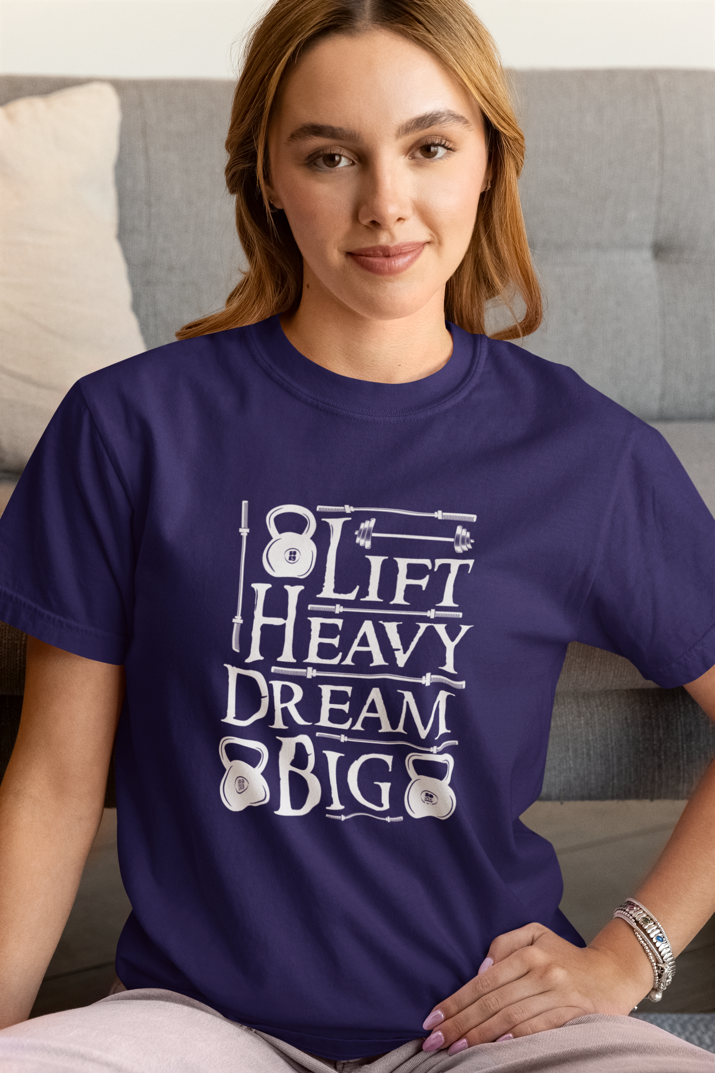 Woman wearing navy Lift Heavy Dream Big t-shirt with kettlebell design.