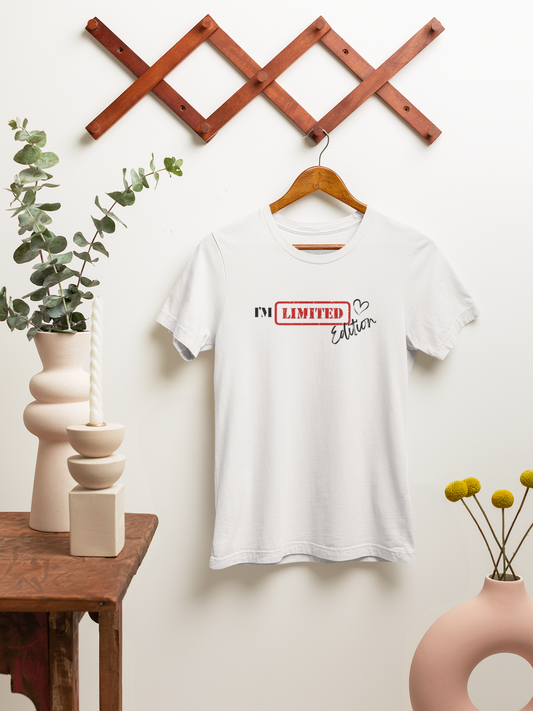 Flat lay of white “I’m Limited Edition” t-shirt displayed on wooden backdrop with small plant – bold and minimal aesthetic