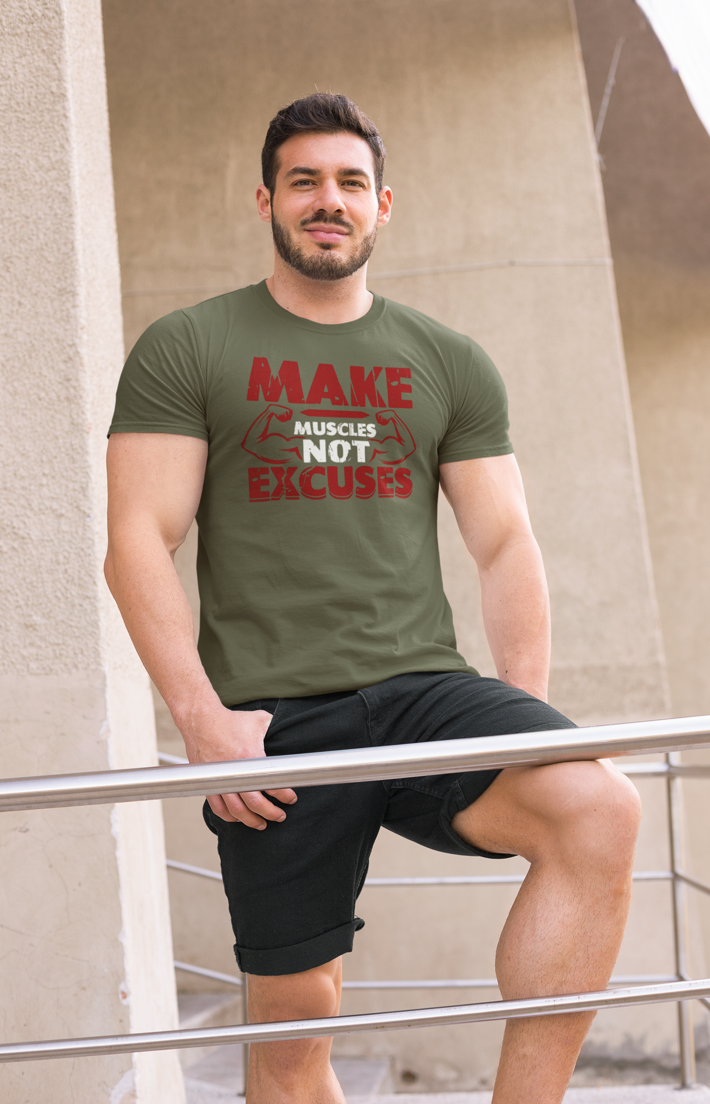 Man lifting barbell in olive green gym t-shirt with bold text “Make Muscles Not Excuses,” workout training apparel.