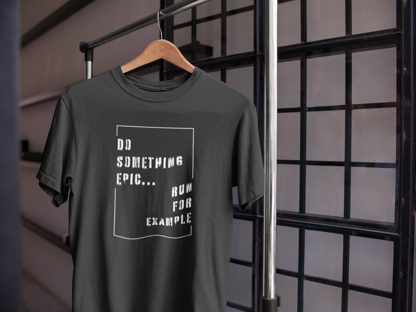 Black motivational t-shirt hanging on wooden hanger near window – Do Something Epic Run for Example design