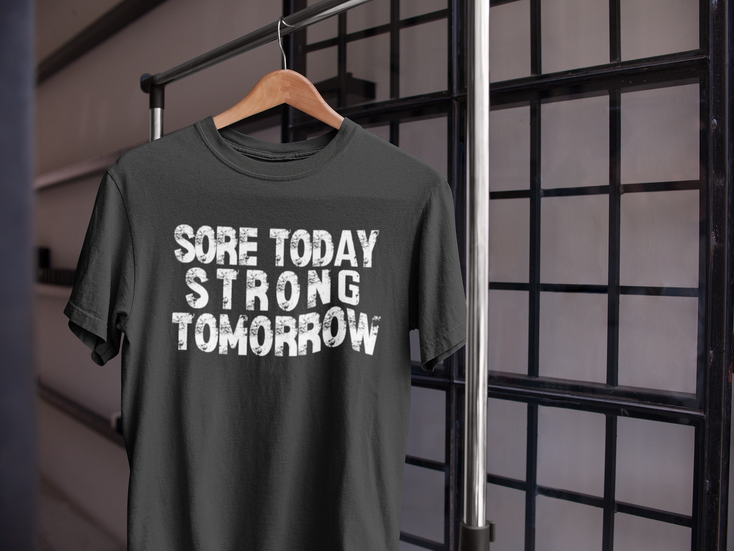 Black gym t-shirt on hanger with "Sore Today Strong Tomorrow" motivational quote – fitness apparel flatlay