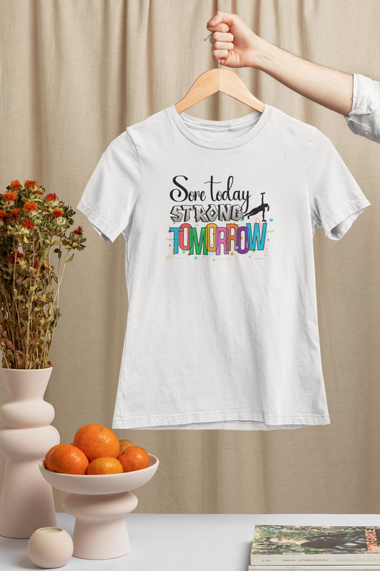 White "Sore Today Strong Tomorrow" women's workout shirt hanging indoors – slim fit motivational gymwear