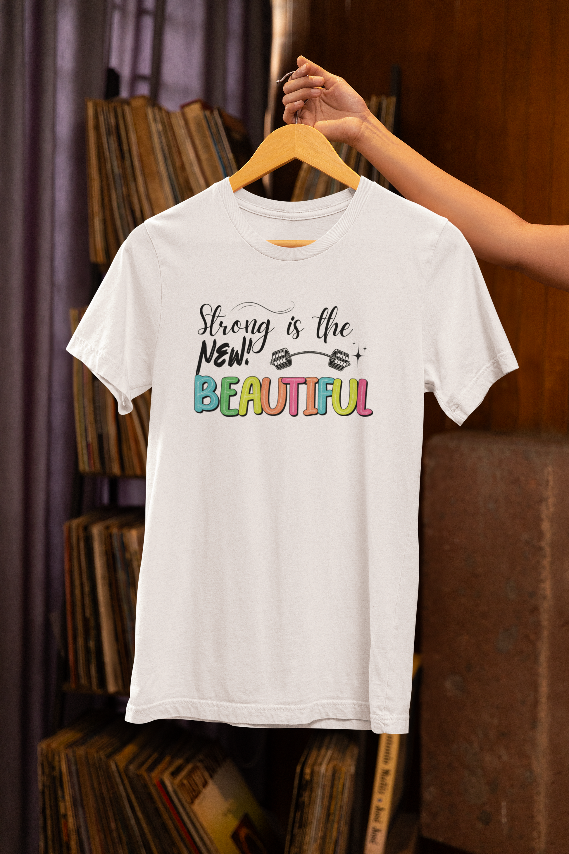 Woman holding "Strong is the New Beautiful" white t-shirt – motivational fitness apparel