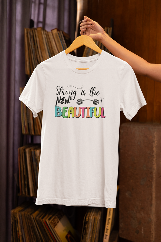Woman holding "Strong is the New Beautiful" white t-shirt – motivational fitness apparel