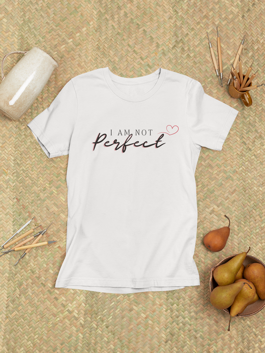 Flat lay of white “I Am Not Perfect” unisex t-shirt with minimal accessories – gym and lifestyle aesthetic